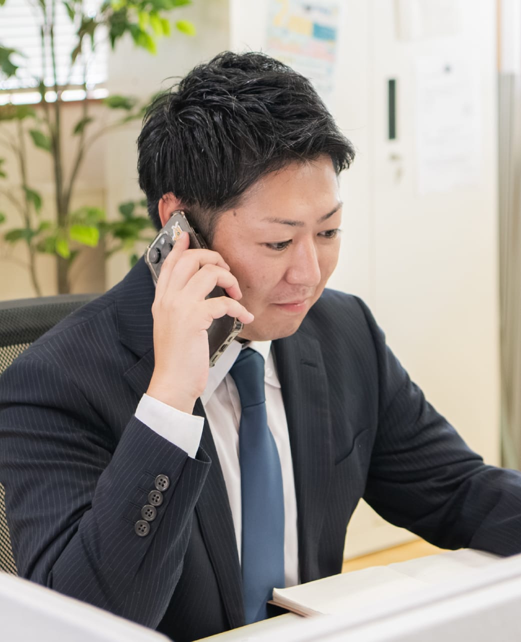 ノートに記入する作業服姿の男性